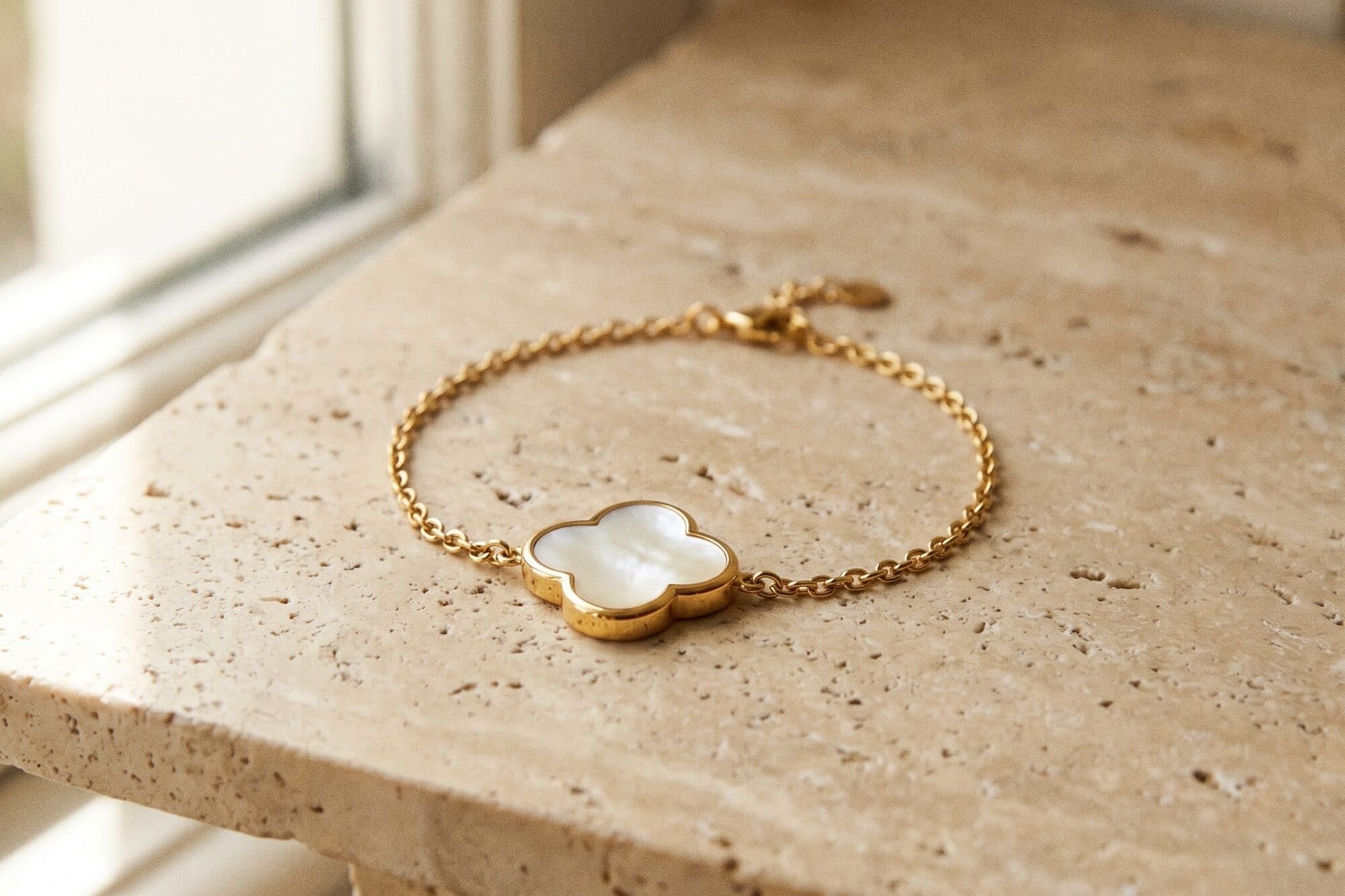 Fine gold jewelry arranged on a warm neutral ground in soft daylight